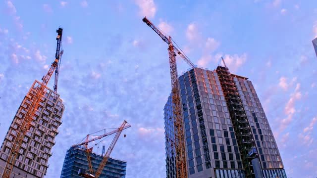 Low angle view of Construction site with cranes at dawn.