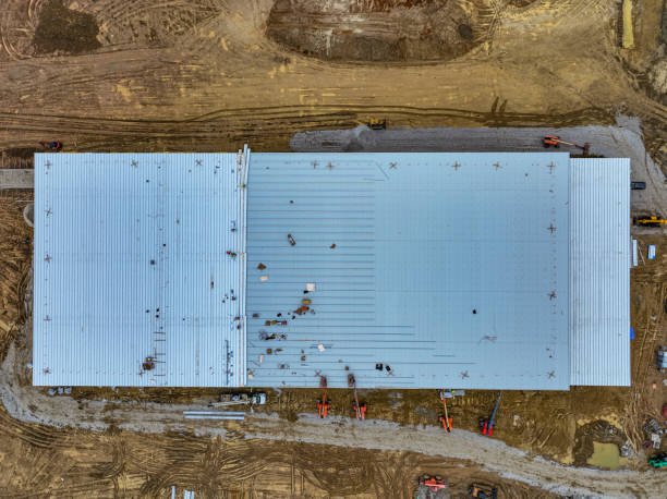 Drone perspective of roofing installation at a new industrial warehouse site.